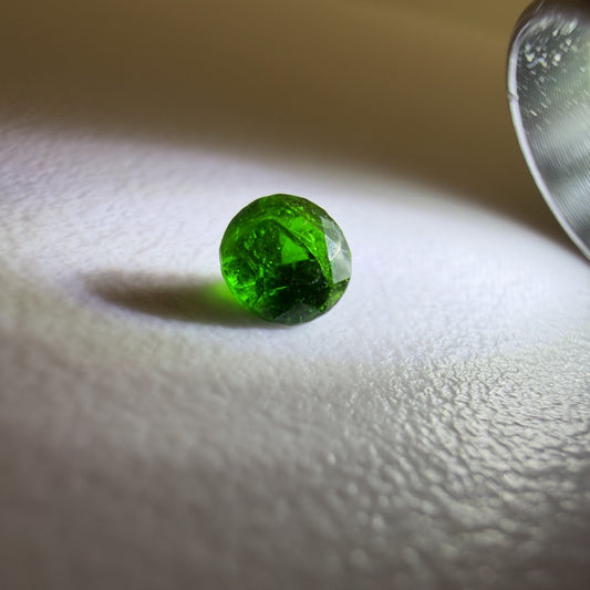 Green gemstone on a textured white surface with a neutral background