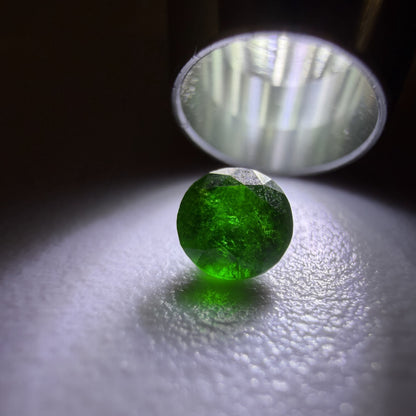Green gemstone under a lamp on a reflective surface
