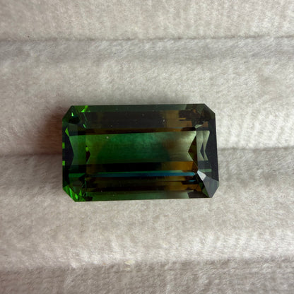 Rectangular green gemstone on a gray fabric background