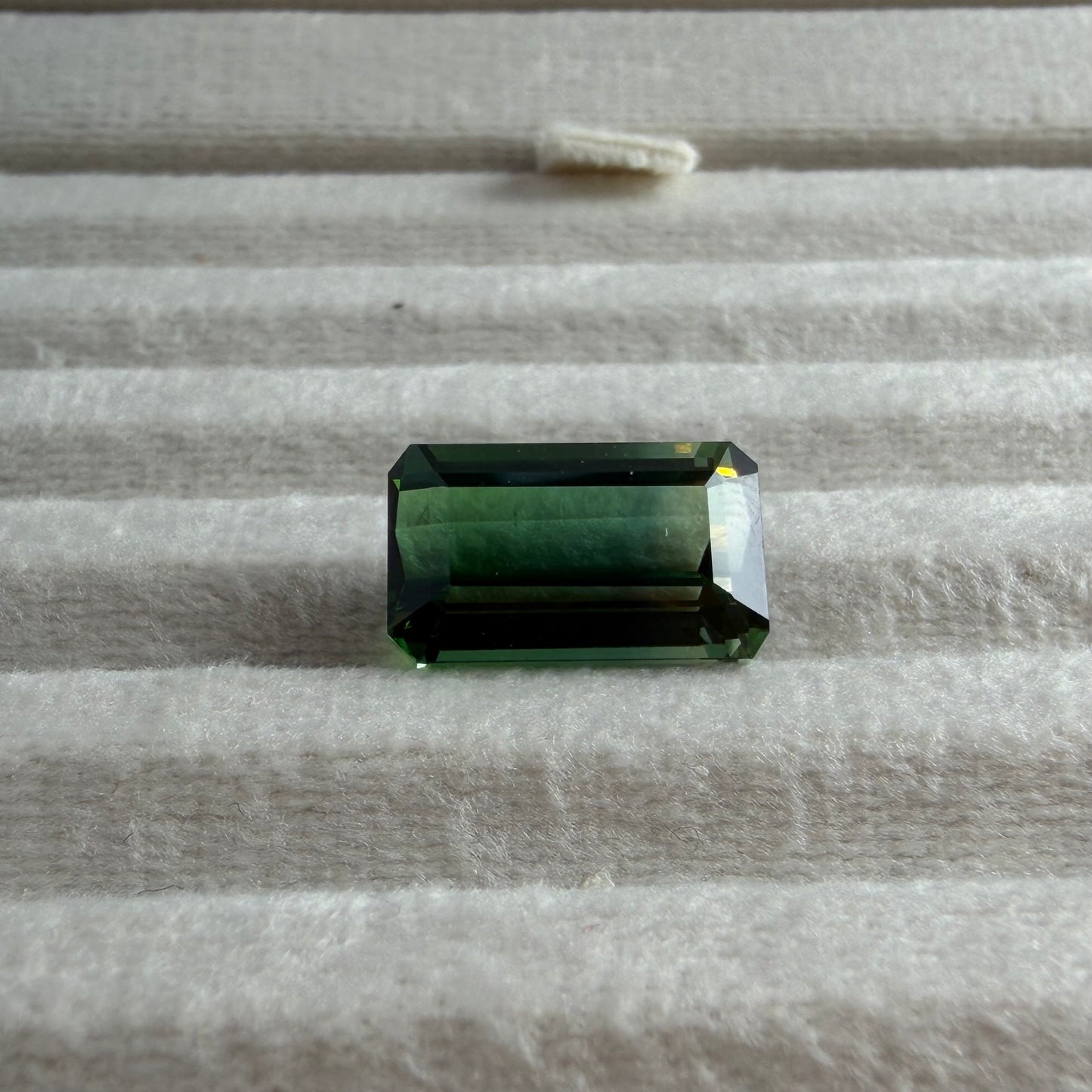 Green gemstone on a textured gray surface