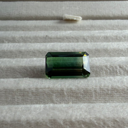 Green gemstone on a textured gray surface