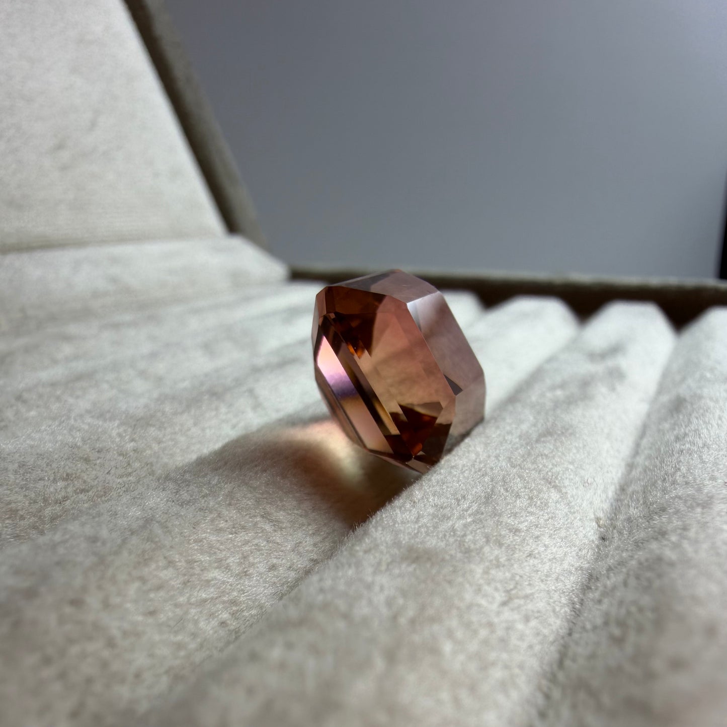 Faceted gemstone on a textured surface with a neutral background