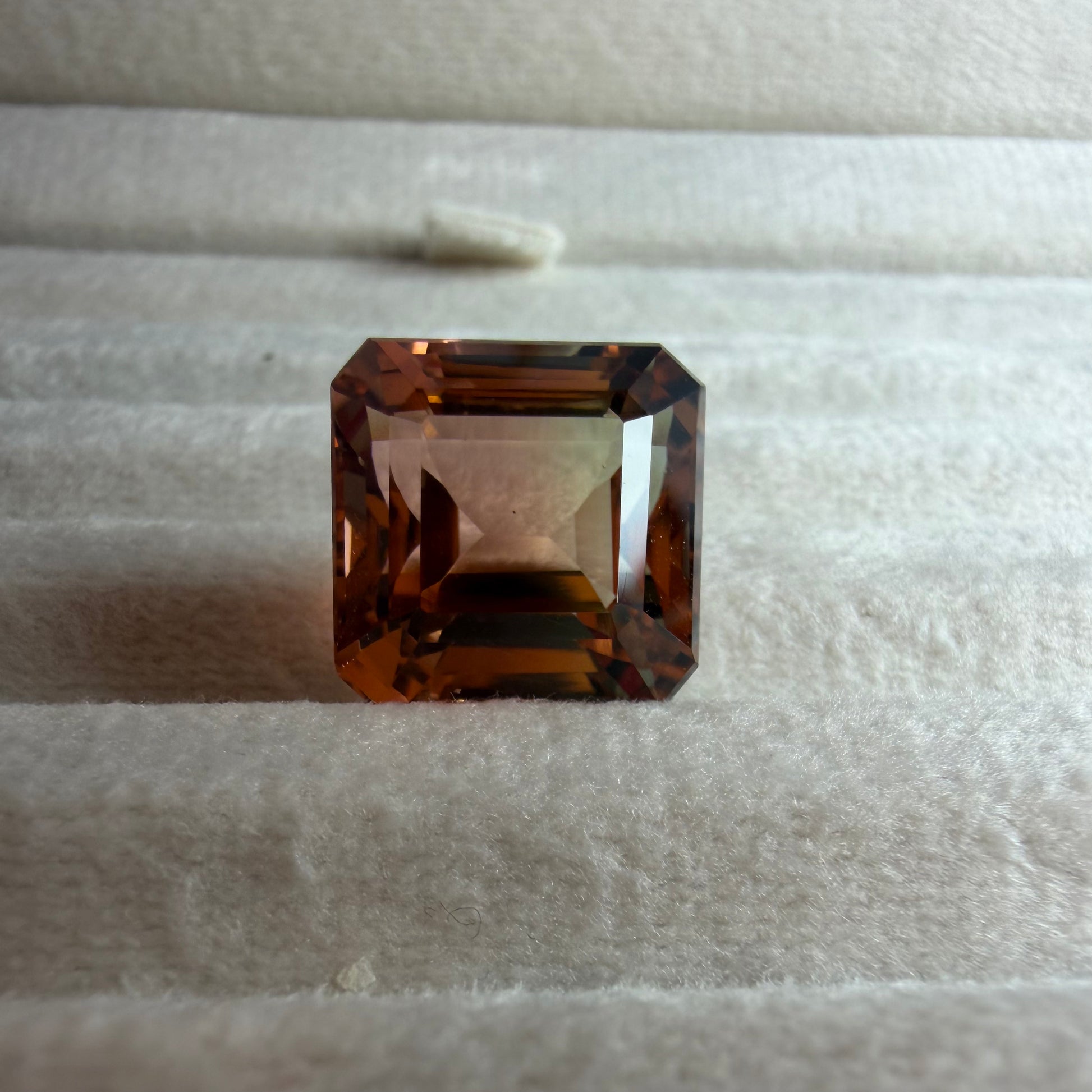 Square-cut brown gemstone on a textured white surface
