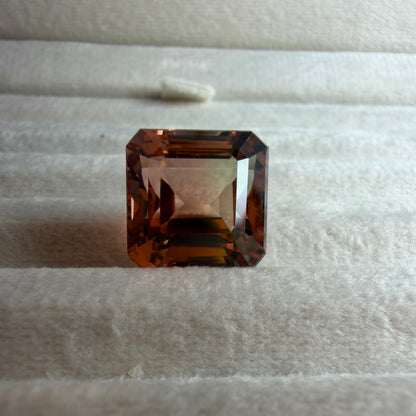Square-cut brown gemstone on a textured white surface