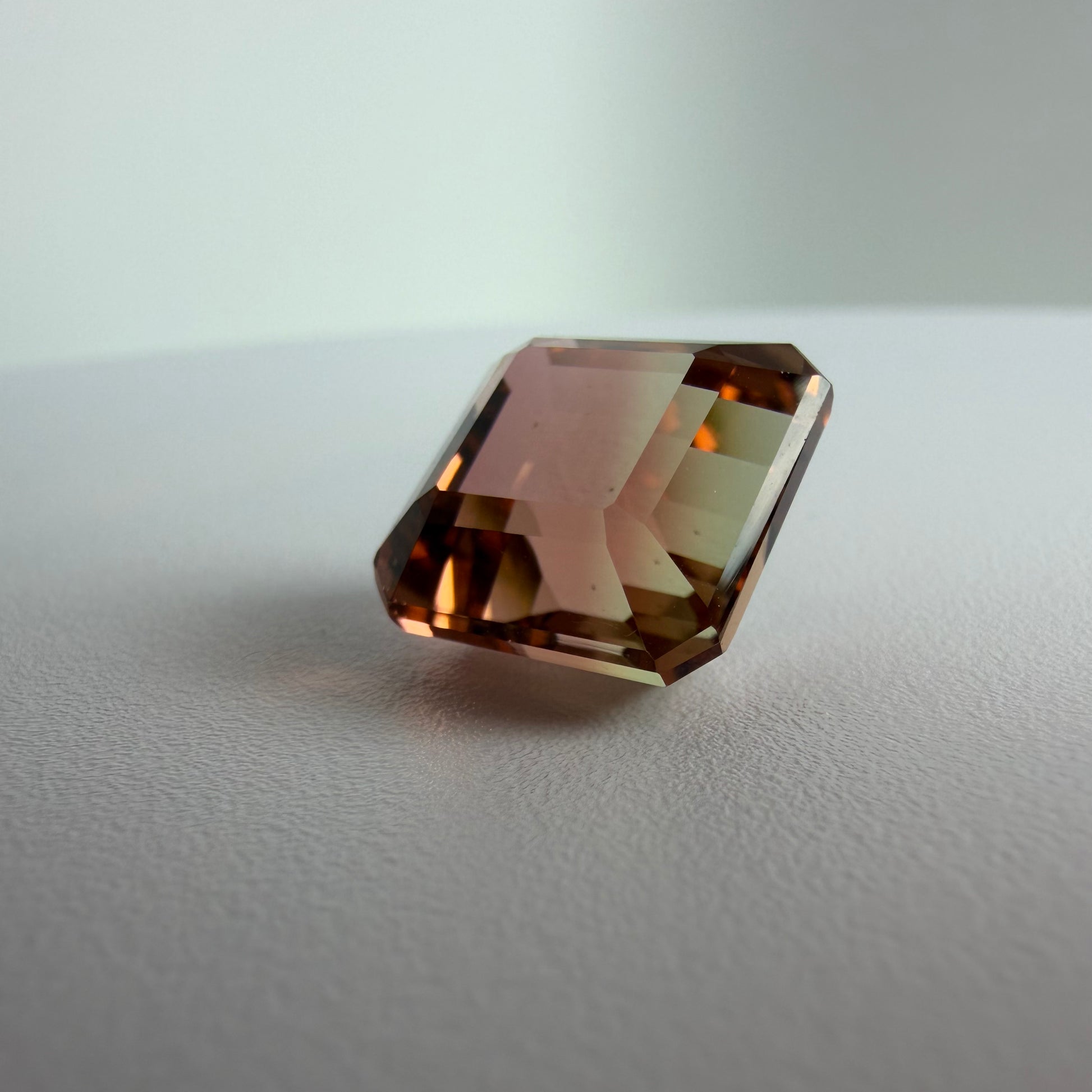 Brown gemstone on a light gray surface with a neutral background