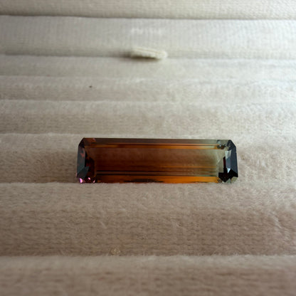 Rectangular brown gemstone on a textured beige surface