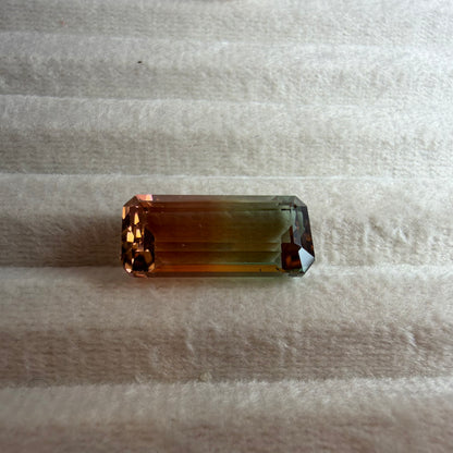 Rectangular multicolored gemstone on a textured beige surface