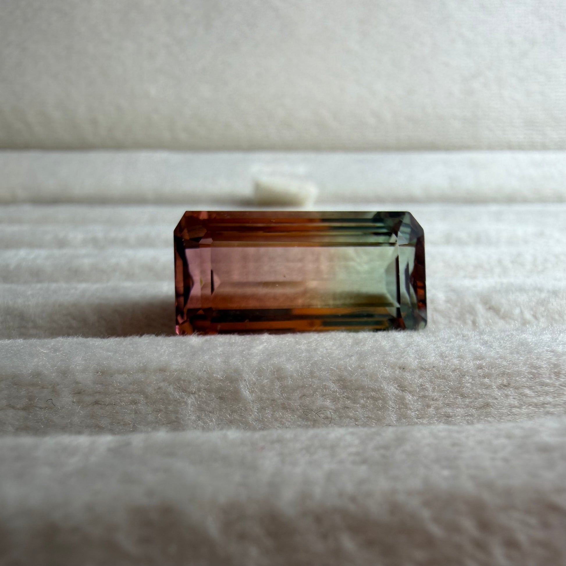 Multicolored rectangular gemstone on a textured white surface