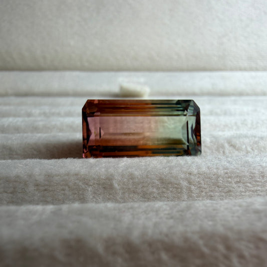 Multicolored rectangular gemstone on a textured white surface